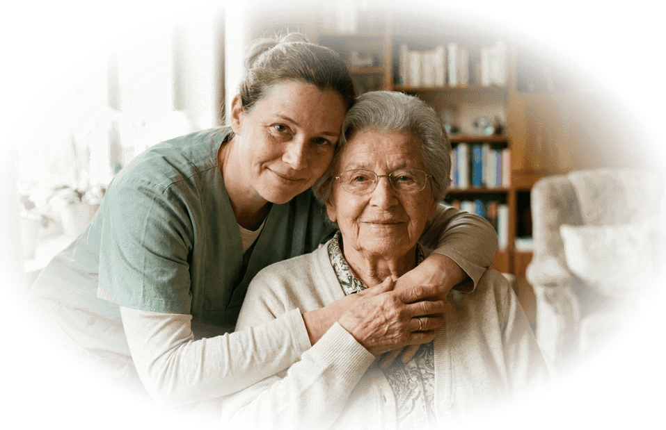 Betreuungskraft umarmt eine Seniorin liebevoll